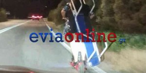 Δύο άτομα μεταφέρουν με πατίνι, ξαπλώστρα θαλάσσης, σε δρόμο ταχείας κυκλοφορίας