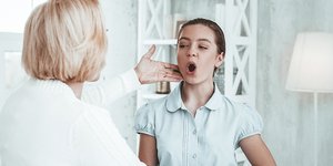 Γιατρός εξετάζει τις φωνητικές χορδές ασθενούς