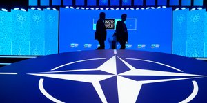 Δύο άνδρες περπατούν μπροστά από το λογότυπο του ΝΑΤΟ, στη σύνοδο κορυφής στην Άγκυρα της Τουρκίας 