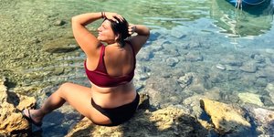 Με φόντο τα κατακάθαρα νερά ποζάρει η Δανάη Μπάρκα καθισμένη σε έναν βράχο