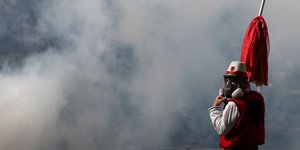 Αλβανός πολίτης με κοντάρι ανάμεσα από καπνούς