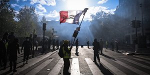 Άνδρας κρατάει τη γαλλική σημαία σε δρόμο του Παρισιού