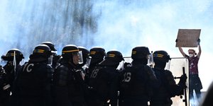 Διαδηλωτής με πλακάτ απέναντι σε αστυνομικούς στη Γαλλία