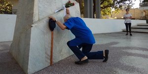 O Mανώλης Γλέζος γονάτισε μπροστά από το μνημείο των «120» / Φωτογραφία: Agrinio News