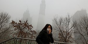 Γυναίκα προσπαθεί να προστατευθεί από την ατμοσφαιρική ρύπανση στο Πεκίνο / Φωτογραφία: ΑΡ