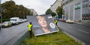 Γερμανοί εργάτες μετακινούν γιγαντοαφίσα της Ανγκελα Μέρκελ σε παλαιότερες εκλογές / Φωτογραφία: AP Images