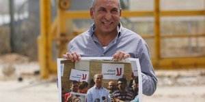 wΠαλαιστίνιος δημοσιογράφος κρατά αφίσα με τον Ομάρ Ναζάλ. Φωτογραφία: AP
