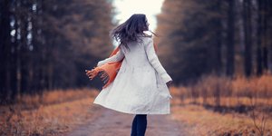 Μια γυναίκα περπατάει χαρούμενη στο πάρκο