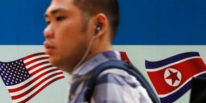 Άντρας περνάει μπρόστα από τις σημαίες των ΗΠΑ και της Β. Κορέας. AP Photo/Andy Wong