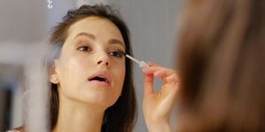 Mια γυναίκα μακιγιάρεται στον καθρέπτη/ Φωτογραφία: Shutterstock