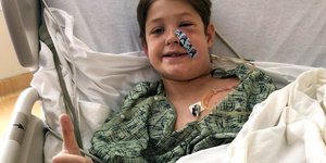 O δεκάχρονος Ξαβιέ Κάνινγχαμ χαμογελά στο κρεβάτι του νοσοκομείου στο Κάνσας