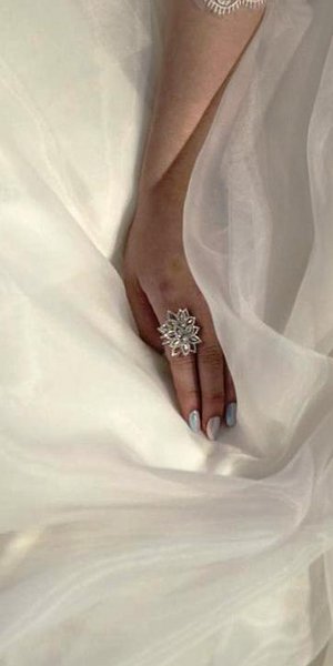 κοντινό σε χέρι νύφης πάνω σε λευκό νυφικό.