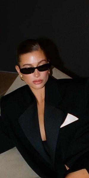 Η Χέιλι Μπίμπερ με μαύρα γυαλιά ηλίου και μαύρο σακάκι.