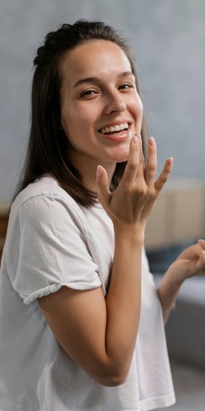 νέα γυναίκα με λευκό t-shirt που φοράει προϊόν χειλιών